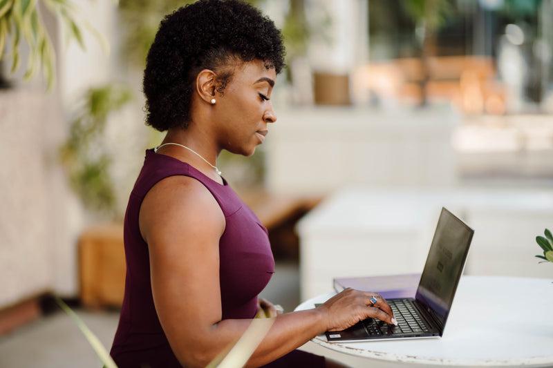 profile of a woman working on her laptop outdoors