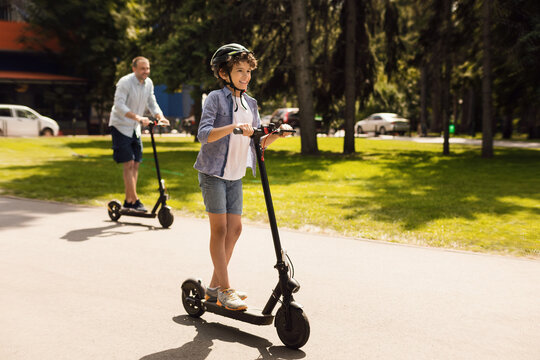 Happy guy with daddy having ride on electric kick scooter