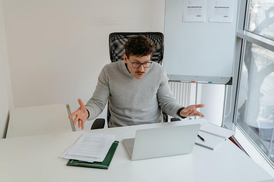 Man in Gray Sweater Wearing Eyeglasses while Working in the Office