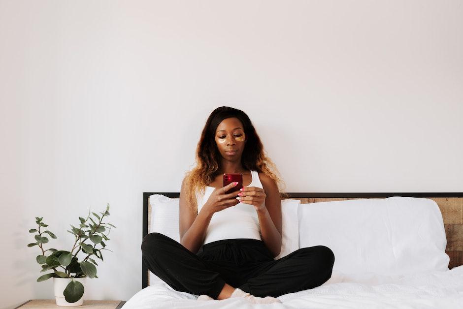 Woman using phone while sitting on bed